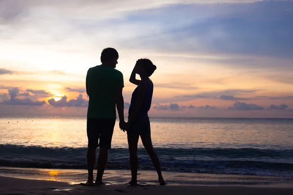 Sunset silhouette of young couple in love walking at beach — Stock Photo, Image