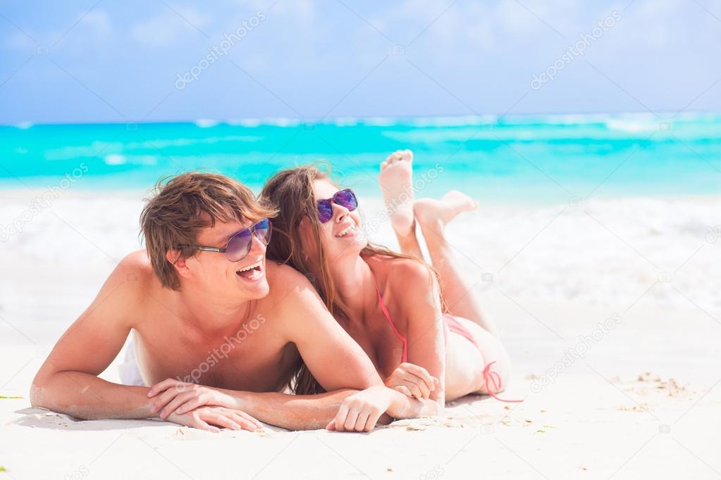 happy young couple lying on a tropical beach in Barbados