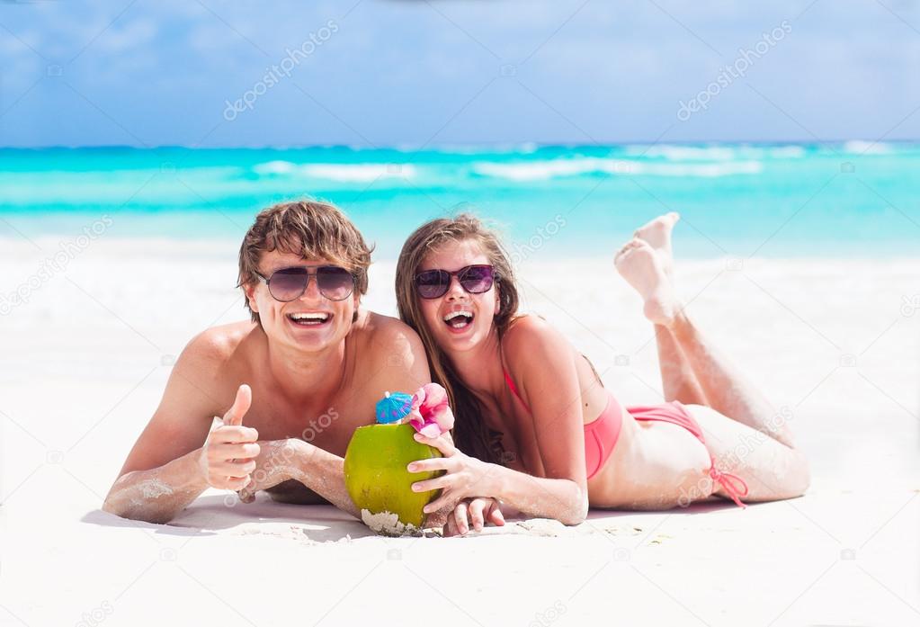 couple lyind and drinking a coconut cocktail on a tropical beach in Barbados