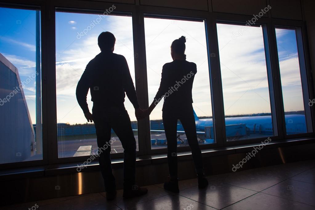 Silhouette of a couple holding hands and waiting at airport terminal