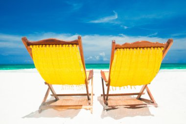 iki sarı plaj sandalyeleri ve kum plaj şemsiyesi. Tatil