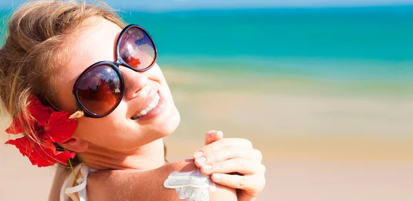 Mujer joven en gafas de sol poniendo crema solar en el hombro —  Fotos de Stock