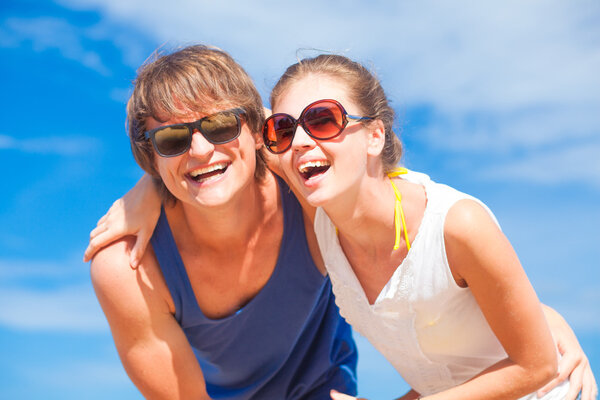 Portrait of happy young couple in sunglasses having fun on tropical beach