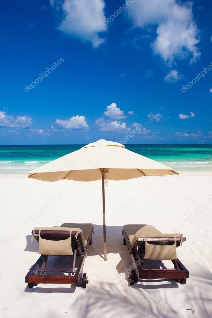 two beach chairs and umbrella on white sand beach. Holidays