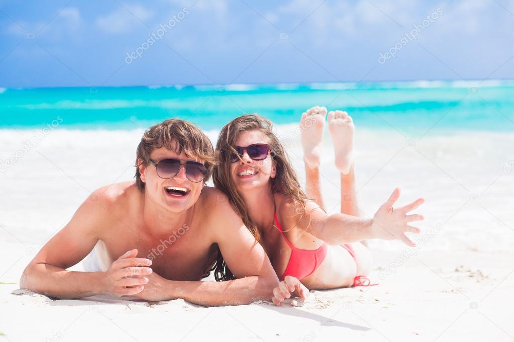 happy young couple lying on a tropical beach in Barbados