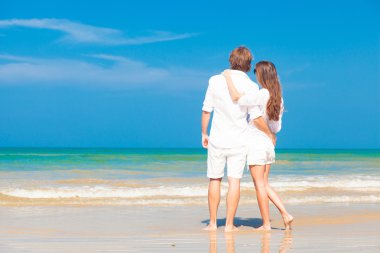 mutlu genç çift Beyaz giysili tropik sahilde eğleniyor