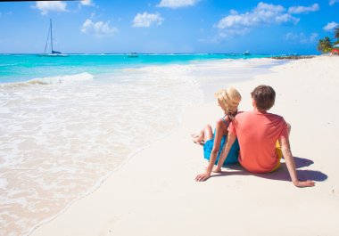 Barbados'taki tropikal bir plajda oturup mutlu genç Çift