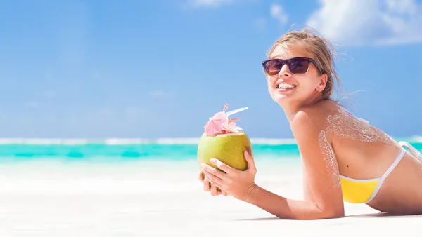 Jovem sorrindo deitado de biquíni com coco na praia — Fotografia de Stock