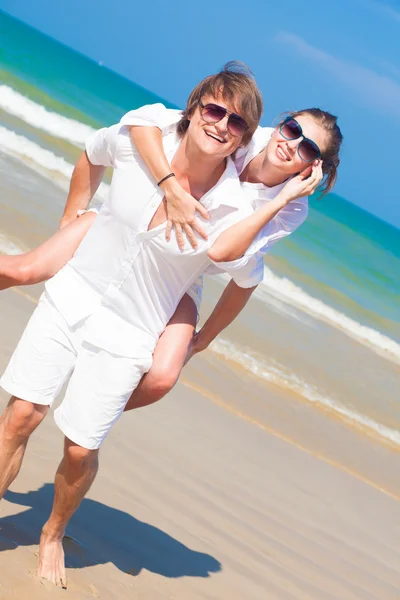 Happy νεαρό ζευγάρι με λευκά ρούχα, διασκεδάζοντας σε τροπική παραλία — Φωτογραφία Αρχείου