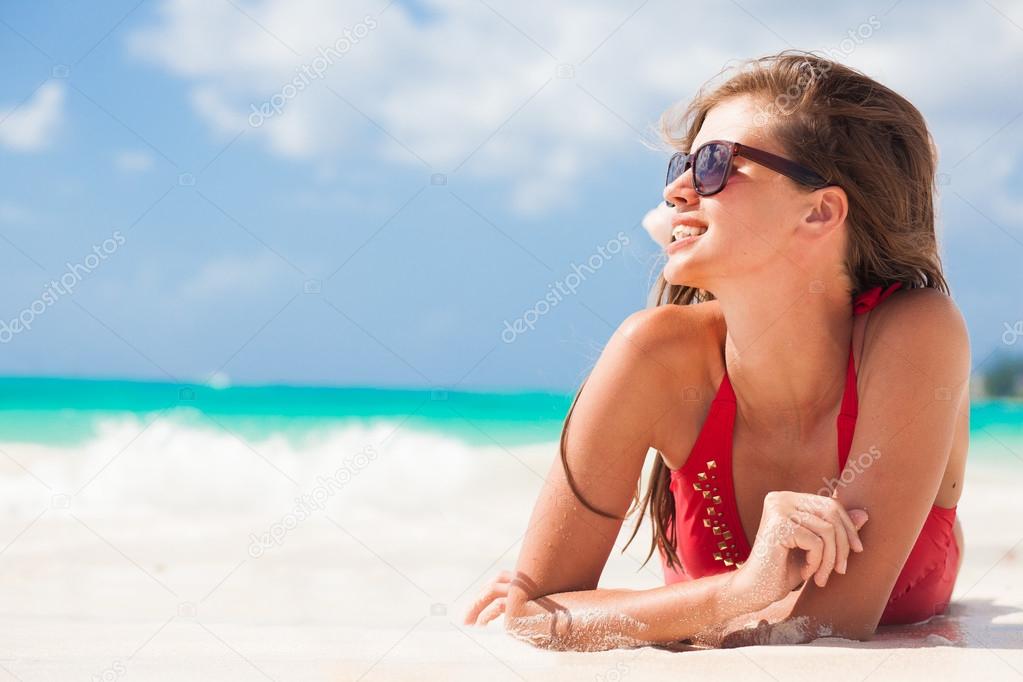 portrait of woman in red swim suit relaxing on tropical beach