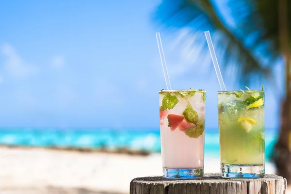 Два бокала охлажденного коктейля мохито и солнцезащитные очки на столе рядом с пляжем — стоковое фото