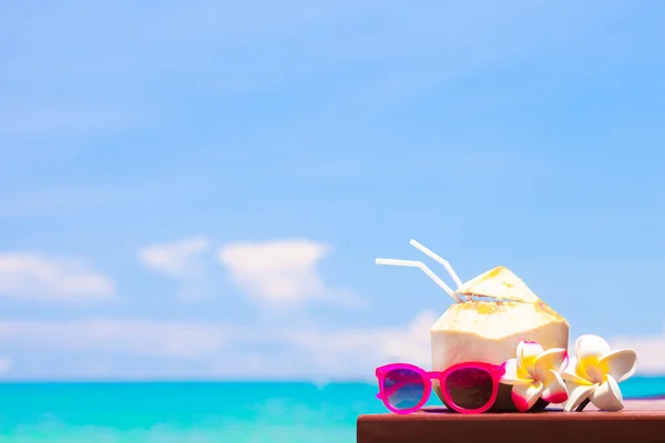 Foto de coquetel de coco fresco e óculos de sol rosa na praia tropical — Fotografia de Stock