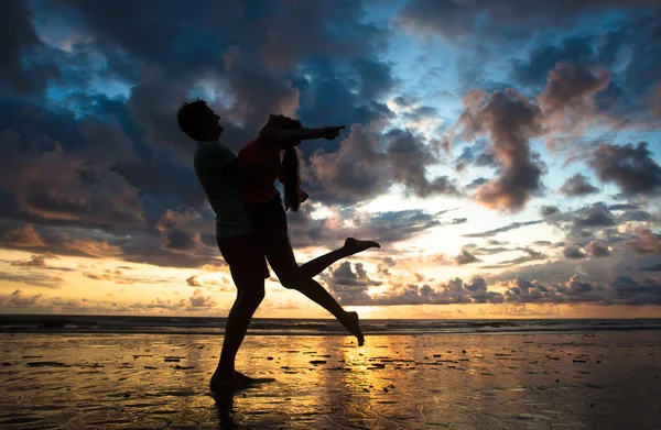在海滩拥抱的年轻夫妇的日落轮廓 — 图库照片