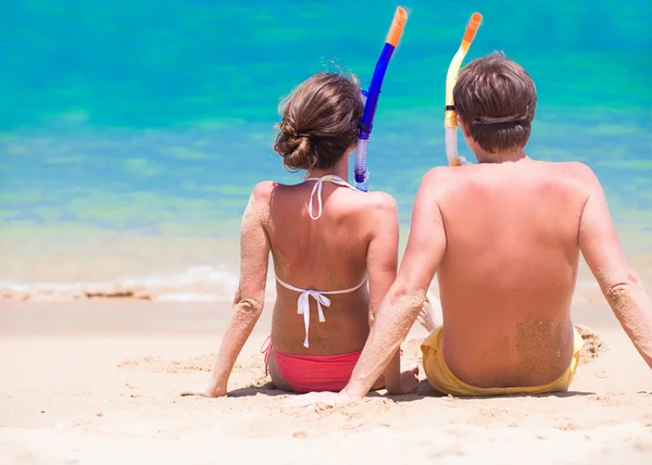 Achteraanzicht van paar met snorkelen vistuig zittend op zand strand — Stockfoto