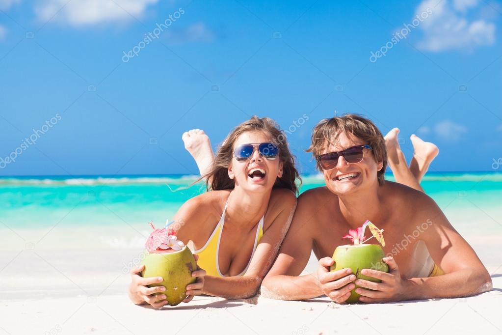 couple lying on a tropical beach in Barbados and drinking a coconut cocktail