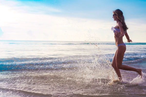 Donna spensierata che corre al tramonto sulla spiaggia. vacanza vitalità concetto di vita sana. gocce d'acqua — Foto Stock