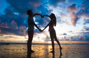 Sunset beach adlı elele aşık genç çift silüeti