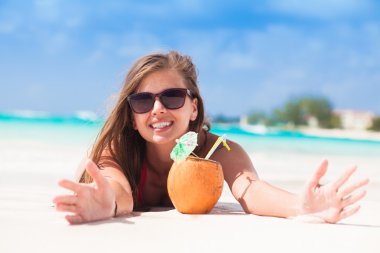 Happy young woman smiling with ccoconut at the beach