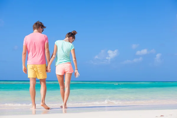 Вид сзади счастливой романтической молодой пары, идущей по пляжу — стоковое фото