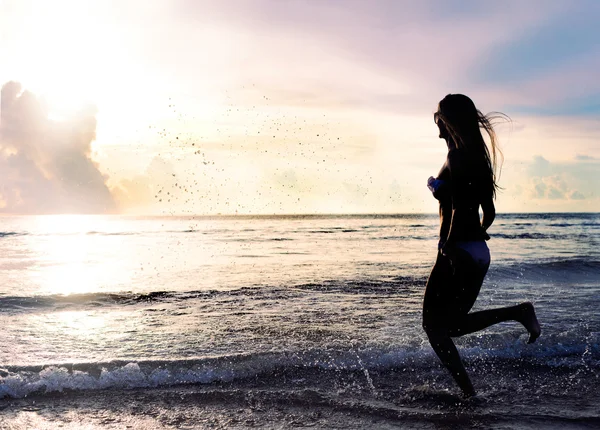 Mujer despreocupada corriendo al atardecer en la playa. vacaciones vitalidad concepto de vida saludable. gotas de agua Fotos de stock libres de derechos