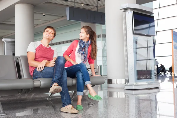 Happy young couple waiting for boarding at airport terminal 免版税图库图片