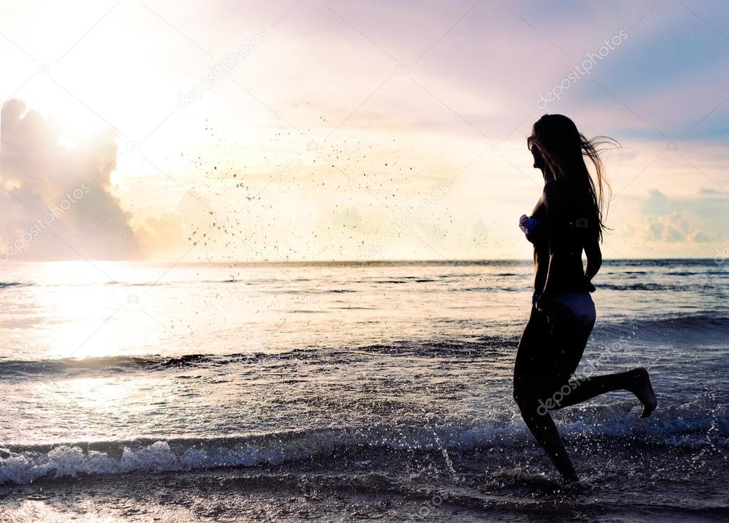 carefree woman running in the sunset on the beach. vacation vitality healthy living concept. water drops