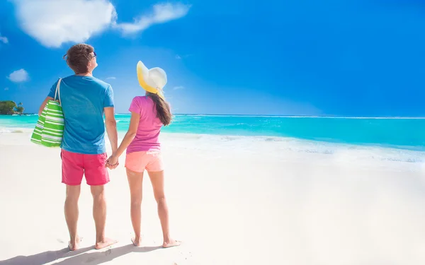 Vista trasera de feliz pareja joven y romántica caminando en la playa —  Fotos de Stock