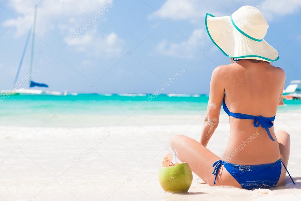 Happy young woman smiling in straw hat with closed eyes on the beach