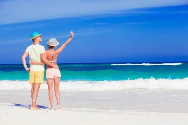 Back view of couple in bright clothes having fun at tropical beach — Stock Photo, Image