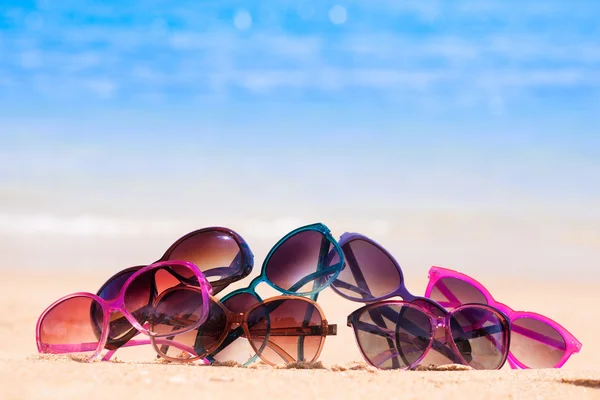 Foto de muitos óculos de sol deitados na praia tropical — Fotografia de Stock