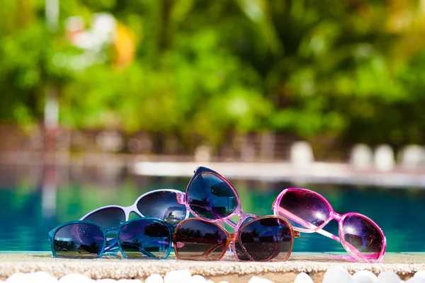 Picture of many sunglasses lying near luxury pool — Stock Photo, Image