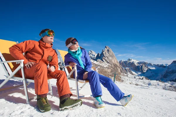 Två snowboardåkare på toppen av berget har roligt sitter på stol schäslong — Stockfoto