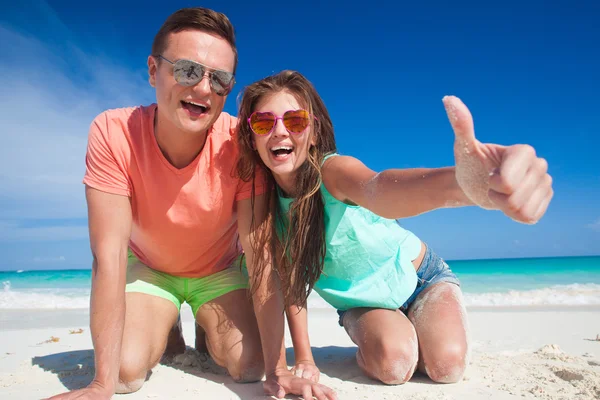 Casal em roupas brilhantes se divertindo na praia tropical — Fotografia de Stock