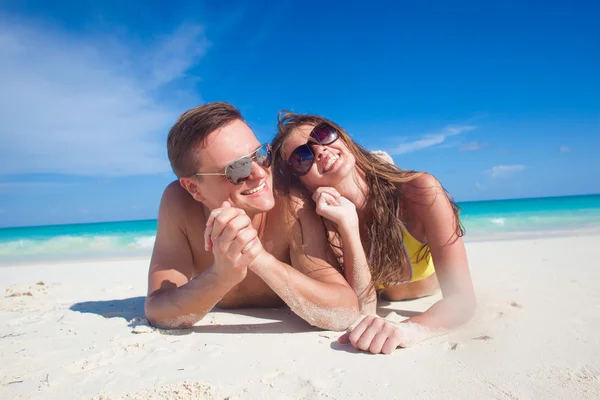 Pareja disfrutando de su tiempo acostado en la arena en la playa tropical —  Fotos de Stock