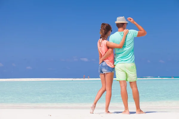 Vista trasera de pareja en ropa brillante abrazándose en la playa tropical —  Fotos de Stock