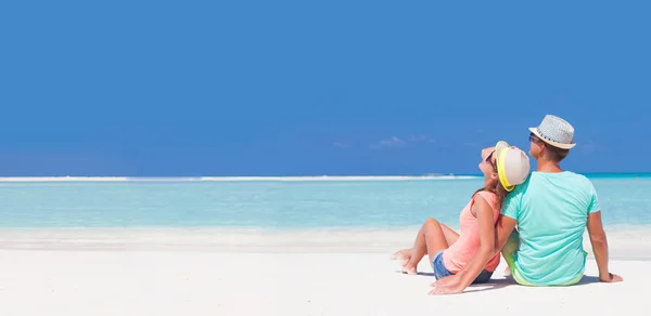 Back view of romantic couple in bright clothes enjoying sunny day at tropical beach — Stock Photo, Image