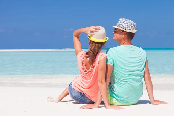 Rückansicht eines romantischen Paares in heller Kleidung, das einen sonnigen Tag am tropischen Strand genießt Stockbild