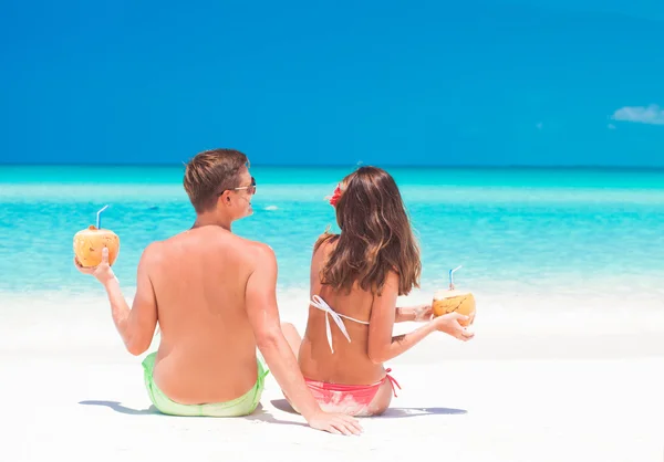 Pareja con cocos en las manos divirtiéndose en la playa tropical — Foto de Stock