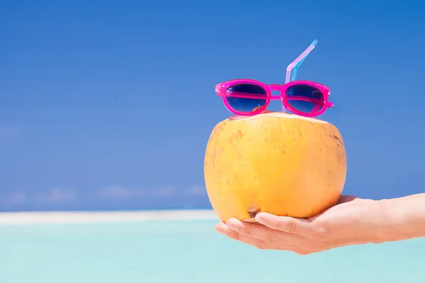 Close up of fresh coconut cocktail in hand on oropical background — Stock Photo, Image