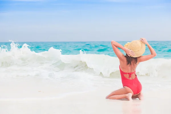 Mujer joven en traje de baño rojo y sombrero disfrutando de un día soleado en la playa tropical —  Fotos de Stock