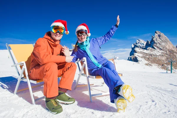 Zwei Snowboarder auf dem Gipfel des Berges haben Spaß, wenn sie in Weihnachtsmützen auf der Sesselliege sitzen — Stockfoto