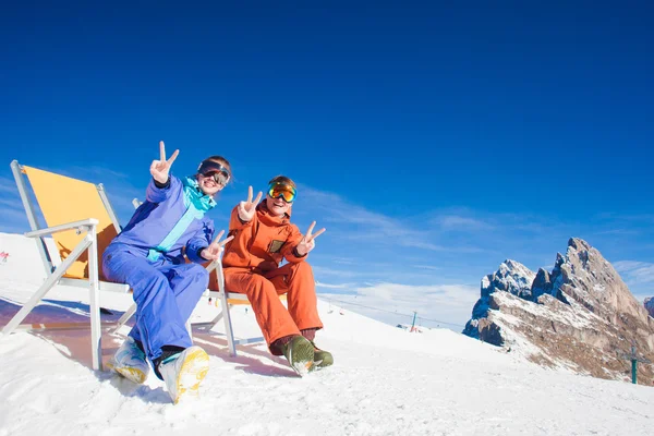 Two snowboarders on top of the mountain having fun sitting on chair chaise lounge — Stock Photo, Image