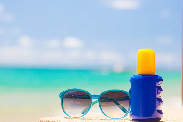 Zonnebrandcrème en zonnebril op zand op tropisch strand — Stockfoto