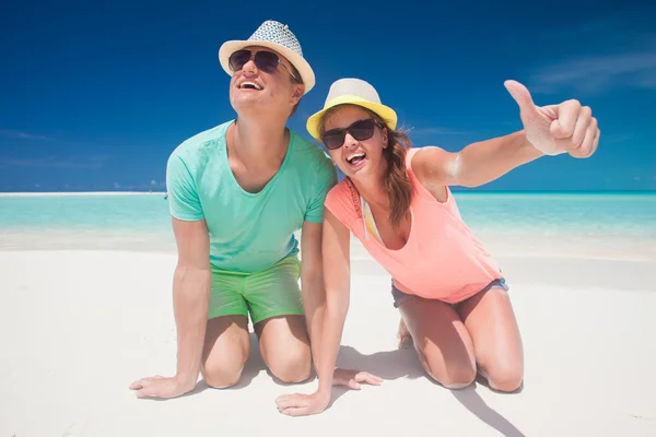 Pareja en ropa brillante y sombreros divirtiéndose en la playa tropical —  Fotos de Stock