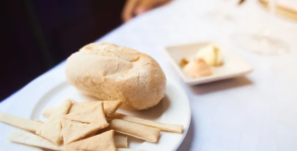 Assortment of freshly baked bread and butter on white table — Stock Photo, Image