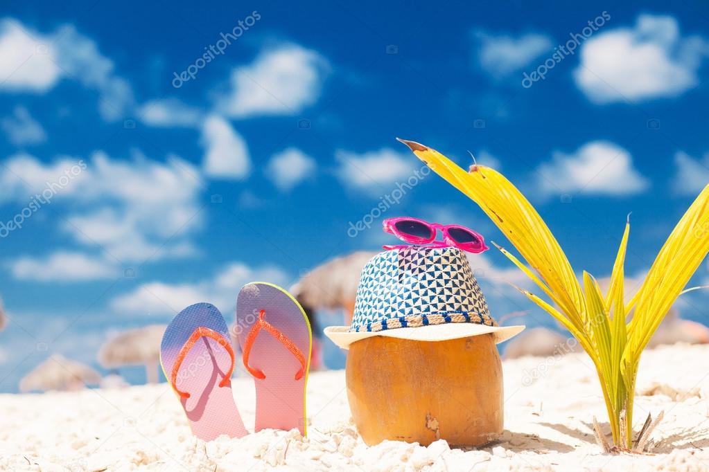 coconut, flip flops, sunglasses and a little palm at white sand beach