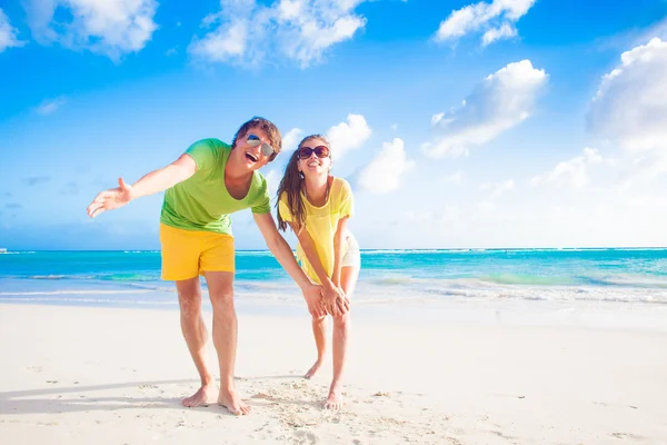 Gelukkige jonge Kaukasische paar in zonnebril glimlachend op strand — Stockfoto