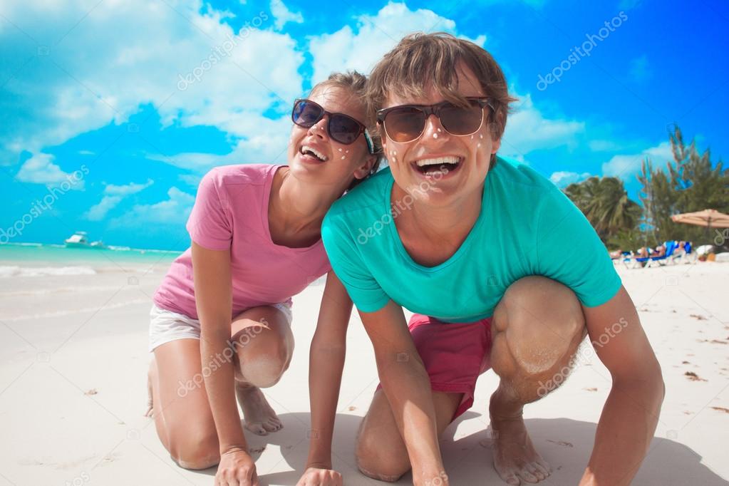 close up of happy young caucasian couple in sunglasses smiling on beach