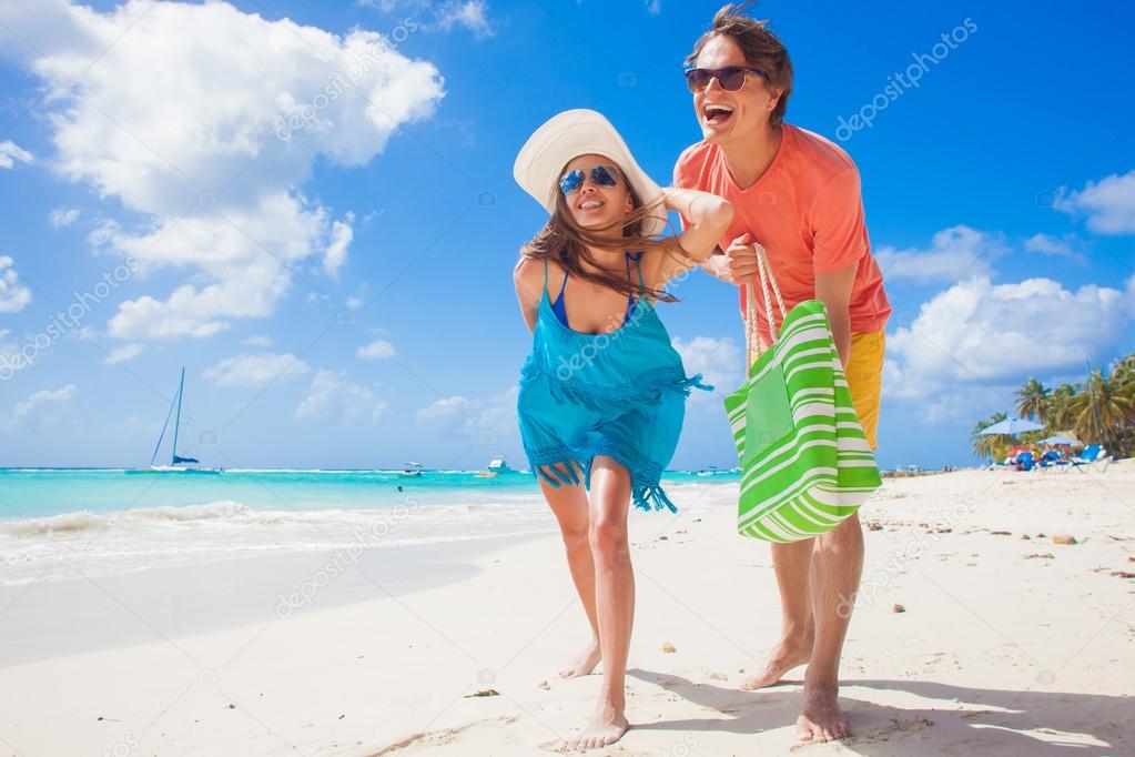 happy young caucasian couple in sunglasses smiling on beach