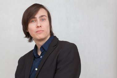 Onun yüzünde sürpriz bir ifade ile beyaz bir arka plan üzerinde siyah bir ceketli beyaz bir genç adam